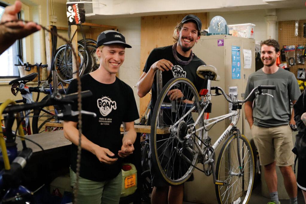 Trois personnes dans l'atelier avec un vélo sur un support